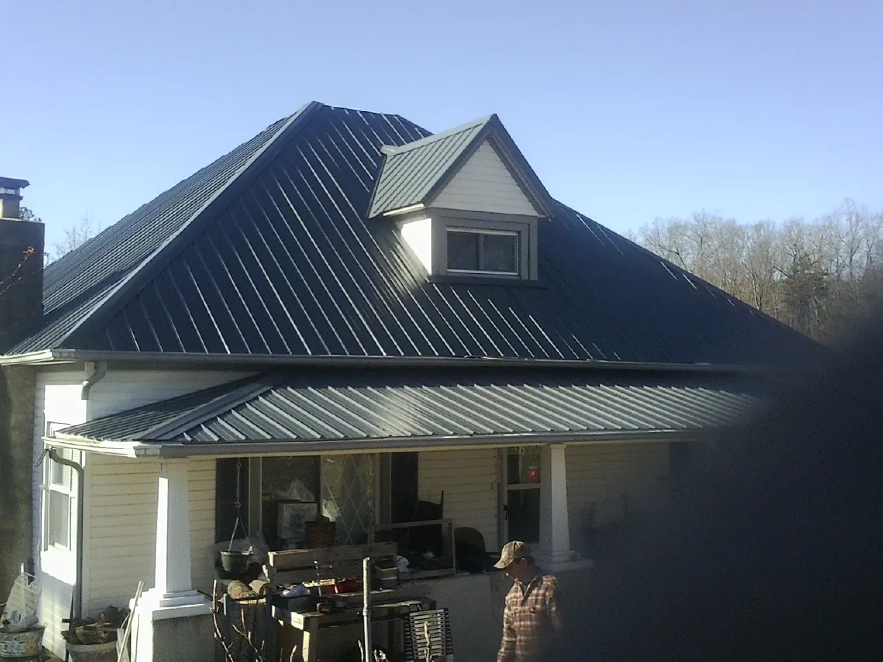 Dark blue standing seam metal roof with a dormer above a front porch in Lakehead