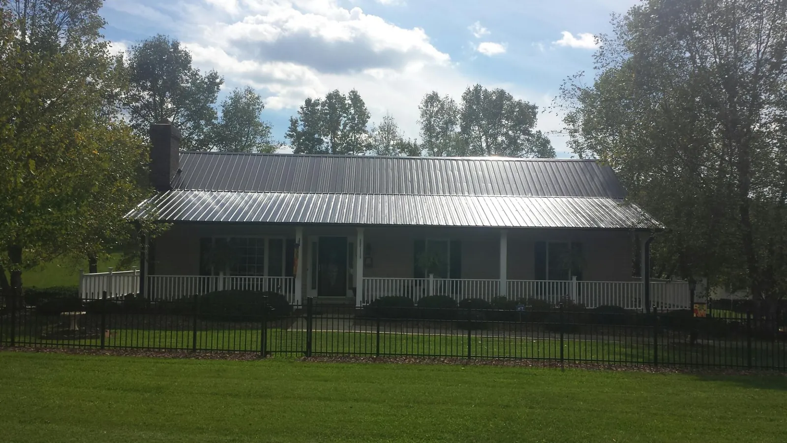 Gray metal roof on a brick ranch with a full width front porch — Gutter Guard Installation work by our crew in Lakehead